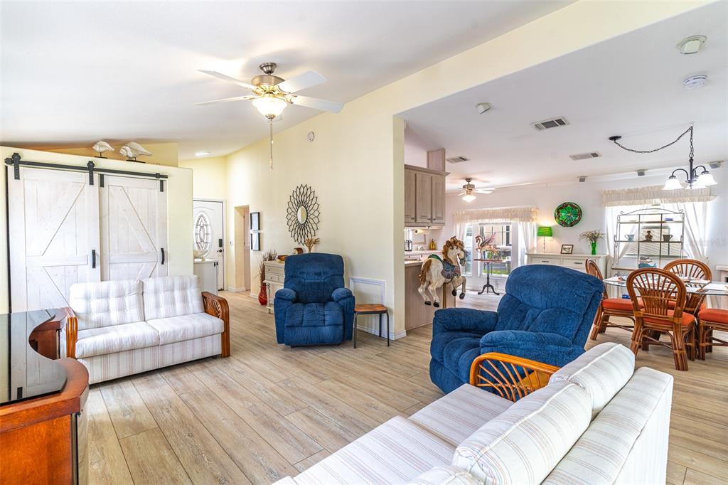 A living room features light wood flooring, two striped sofas, and two blue recliners — 511 PAR PINES BOULEVARD, DAVENPORT, FL