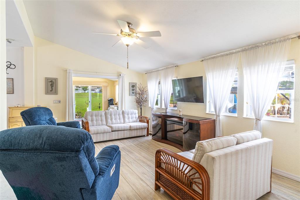A living room features light wood flooring, a ceiling fan, and two sofas with recliners — 511 PAR PINES BOULEVARD, DAVENPORT, FL
