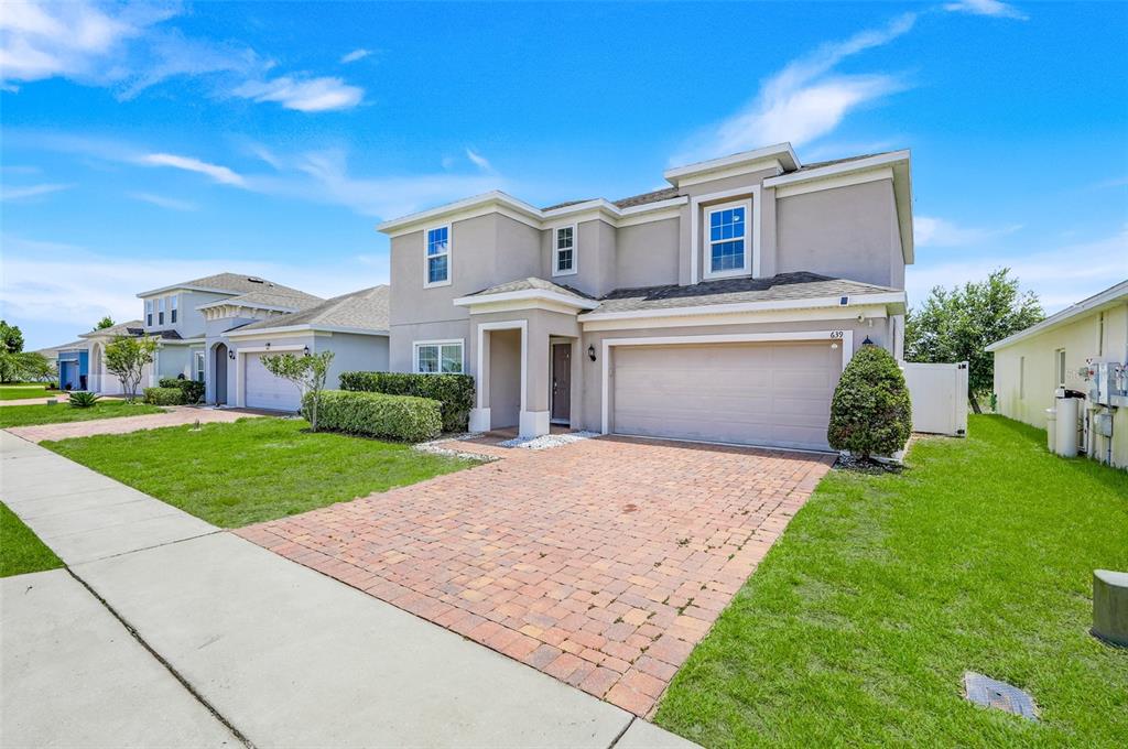A two-story suburban house with a brick paver driveway and a two-car garage — 639 SAMUEL PLACE, DAVENPORT, FL