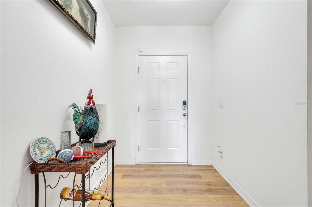 A white-walled entryway features a wood-look floor, a white door, and a decorative console table — 639 SAMUEL PLACE, DAVENPORT, FL