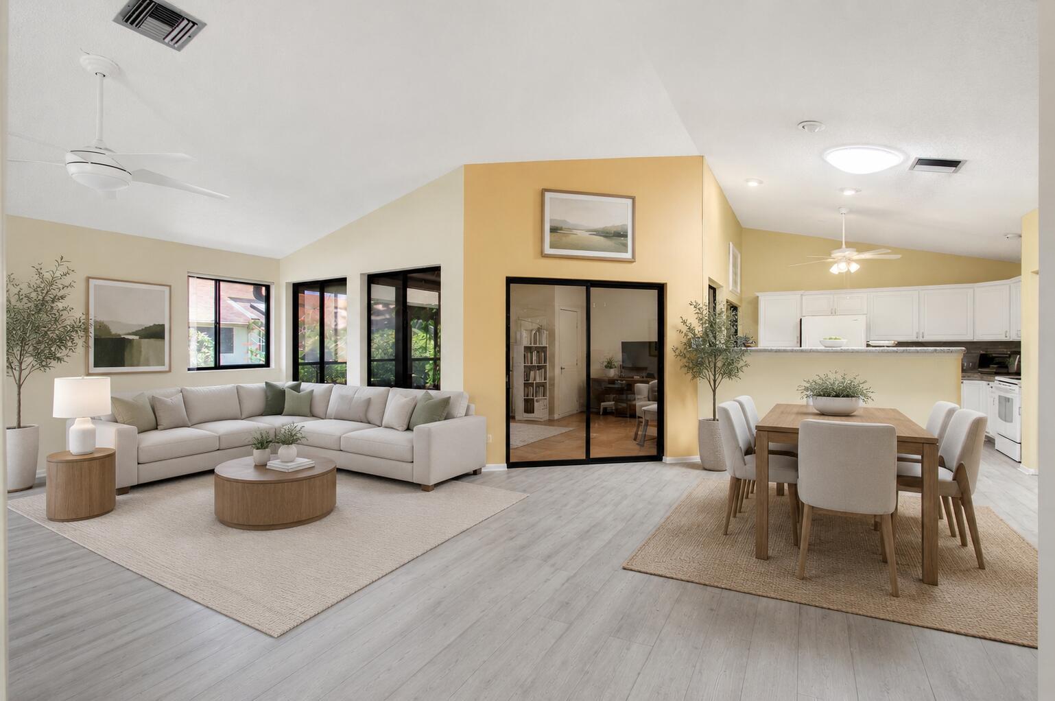 An open-concept living and dining area features light-colored walls, wood-look flooring, and a sectional sofa — 1320 NW 29th Avenue # D, Delray Beach FL 33445, DELRAY BEACH, FL