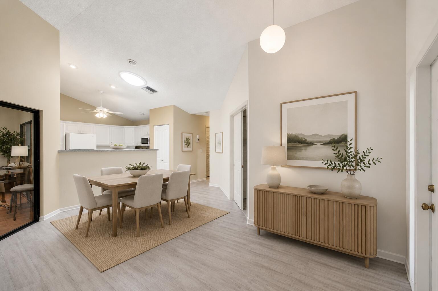 A dining area with a wooden table and chairs sits near a kitchen and entryway — 1320 NW 29th Avenue # D, Delray Beach FL 33445, DELRAY BEACH, FL