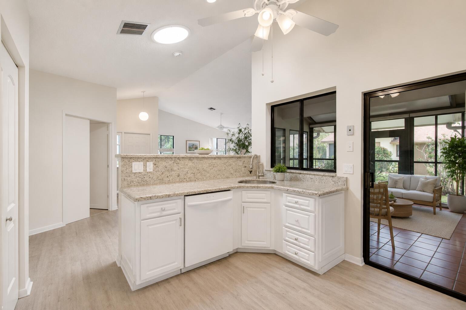 A kitchen with white cabinets, granite countertops, and a view into a screened-in porch — 1320 NW 29th Avenue # D, Delray Beach FL 33445, DELRAY BEACH, FL