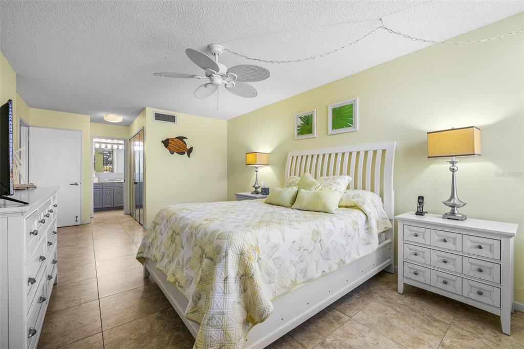 A bedroom features a white bed, two nightstands, a dresser, and light yellow walls — 9495 BLIND PASS ROAD UNIT 204, ST PETE BEACH, FL
