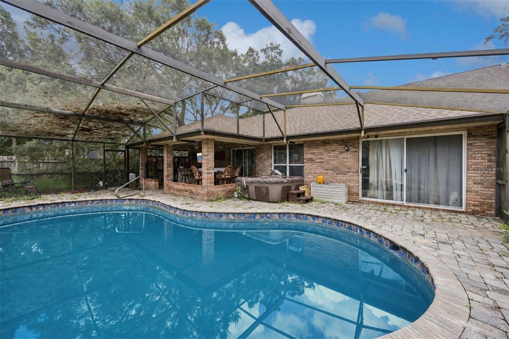 A backyard swimming pool with a screened enclosure, brick patio, and a hot tub — 175 WHITE DOVE AVENUE, ORANGE CITY, FL