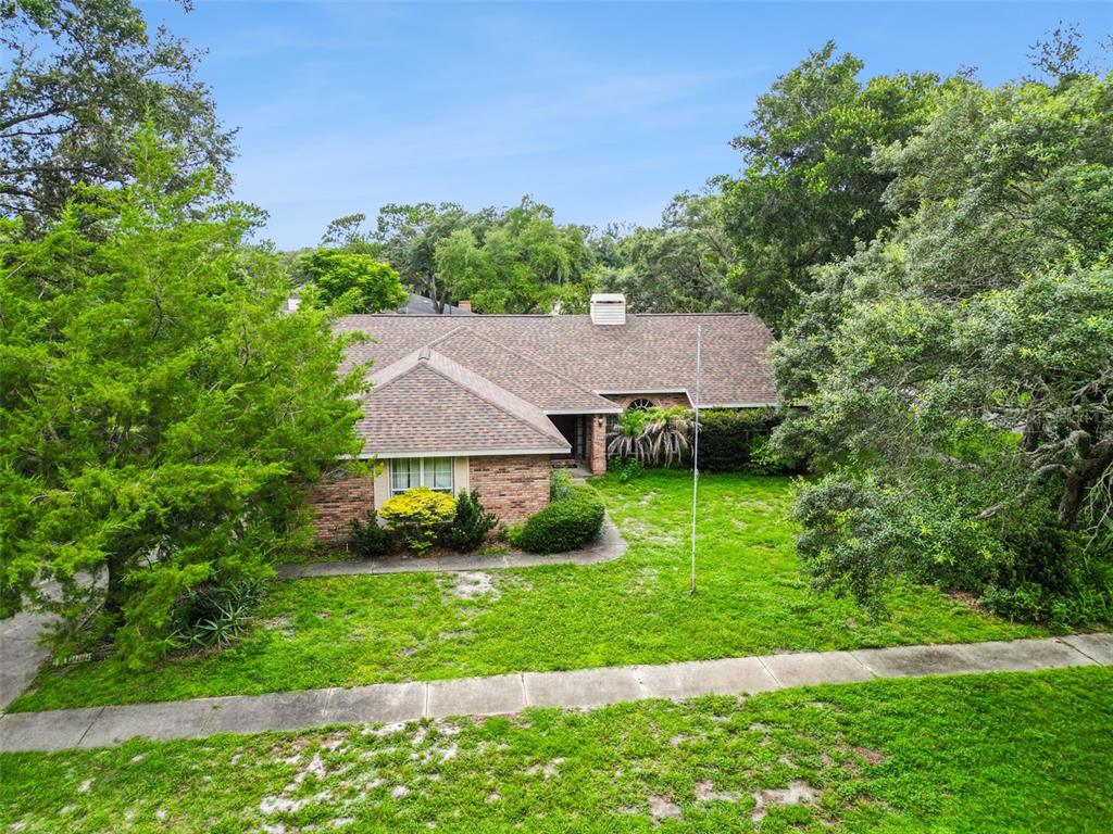 An aerial view of a single-story brick house with a shingled roof and surrounding trees — 175 WHITE DOVE AVENUE, ORANGE CITY, FL