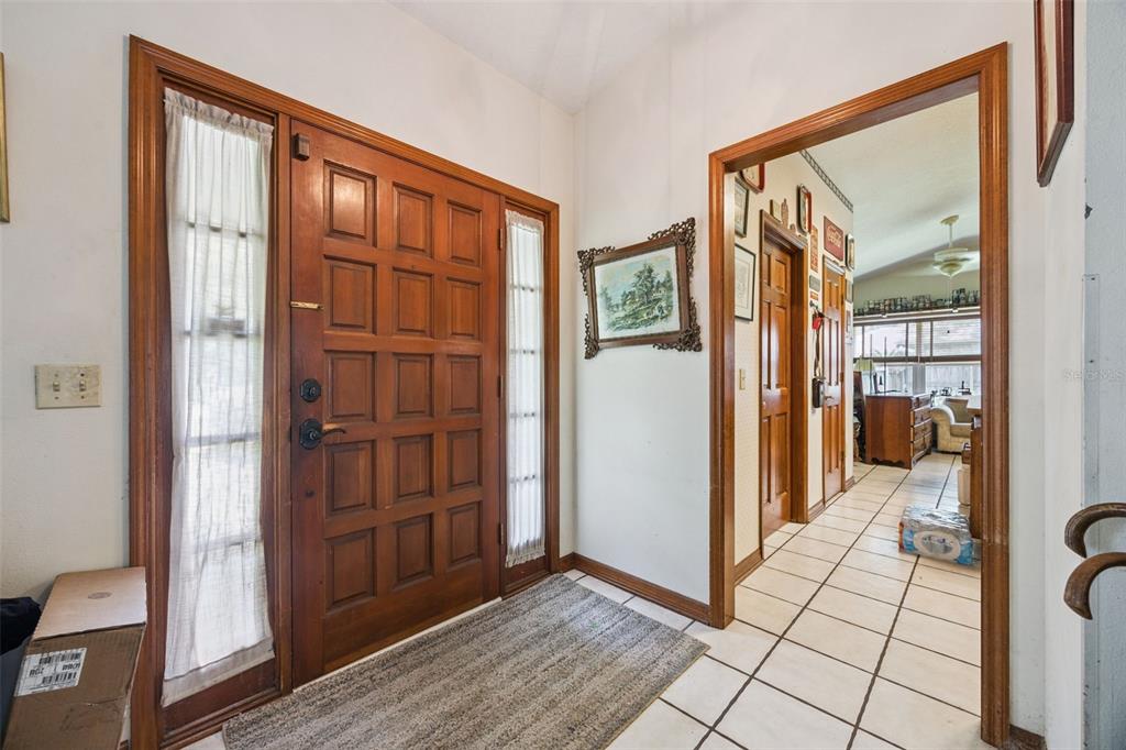 An entryway features a wood paneled front door with sidelights and a tiled hallway beyond — 175 WHITE DOVE AVENUE, ORANGE CITY, FL