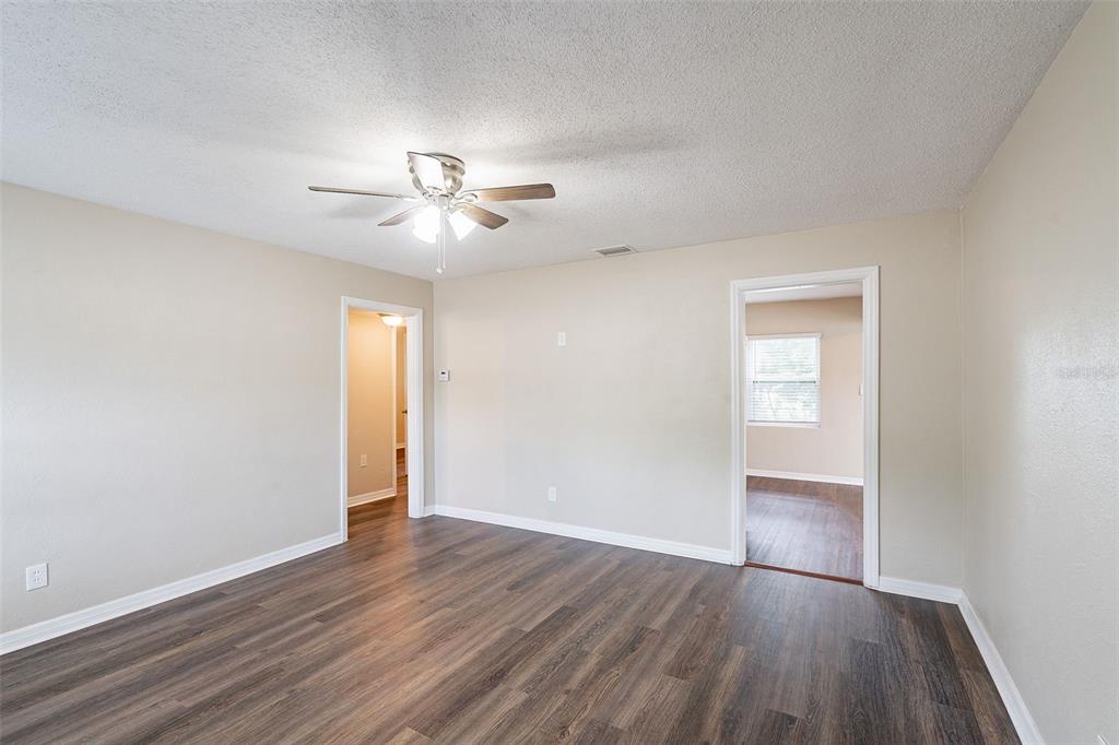 An empty room with wood-look flooring, beige walls, a ceiling fan, and two doorways — 1411 N POWERS DRIVE, ORLANDO, FL