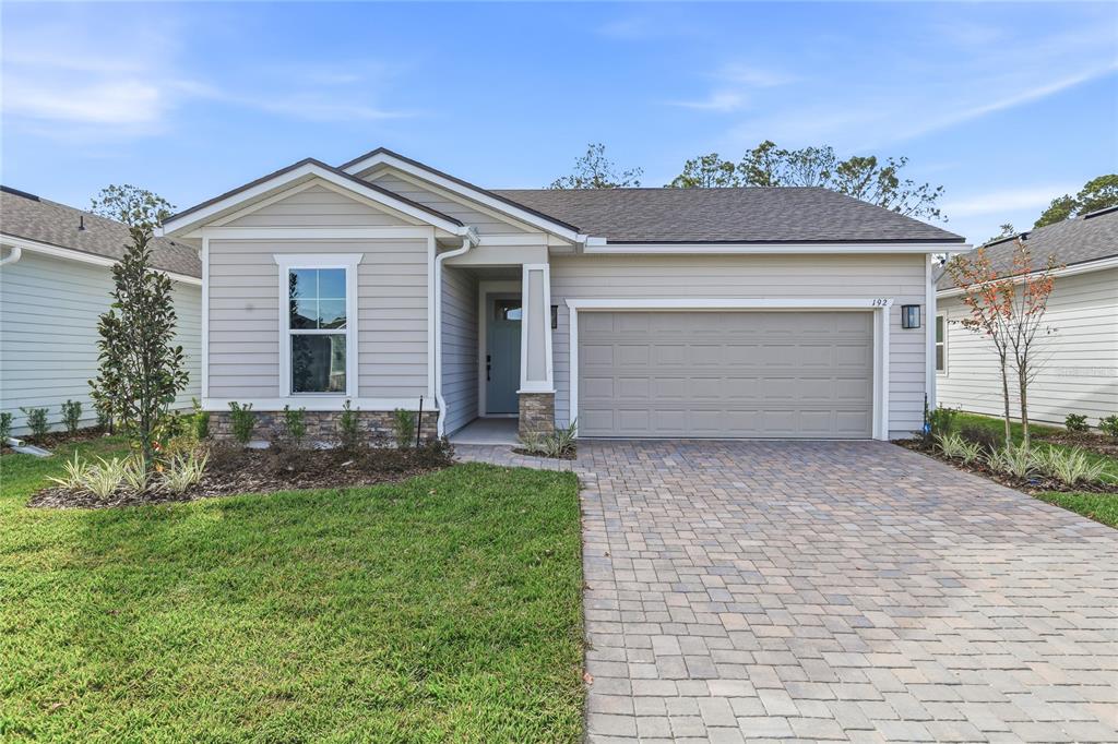 A single-story house with light gray siding, a stone-accented entryway, and a paved driveway — 192 ENCLAVE AVENUE, PALM COAST, FL