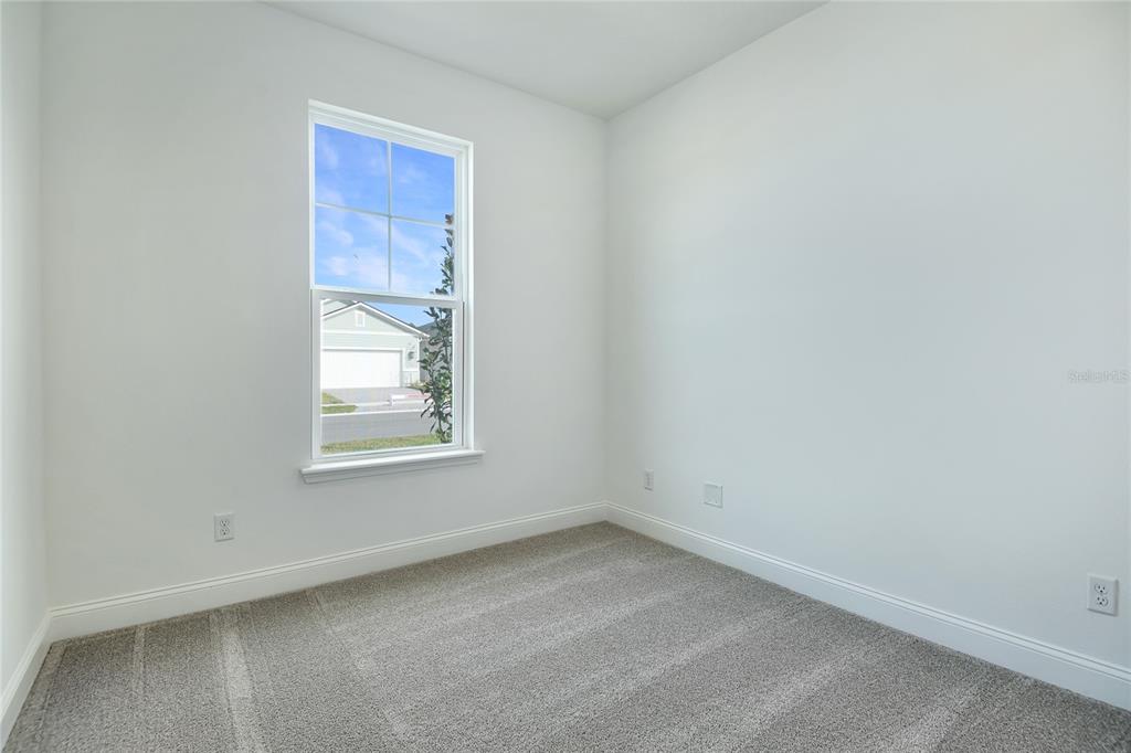 An empty bedroom features white walls, gray carpet, and a single window overlooking a street — 192 ENCLAVE AVENUE, PALM COAST, FL