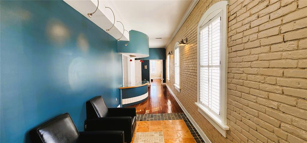 A hallway features a blue wall, a brick wall, black armchairs, and a curved reception desk — 241 E PARK AVENUE, LAKE WALES, FL