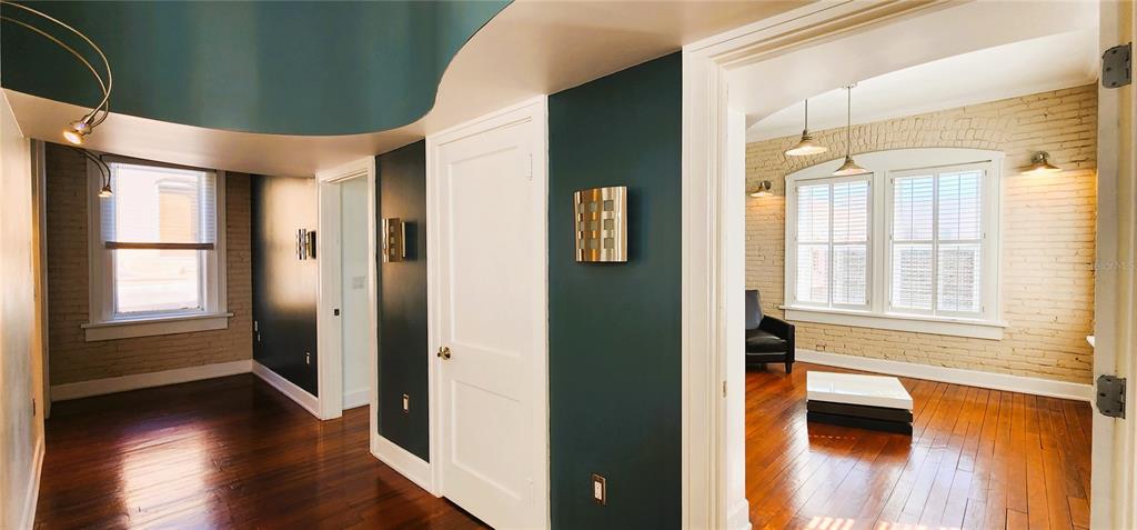 An interior view showing a hallway with dark walls, wood floors, and an adjacent room — 241 E PARK AVENUE, LAKE WALES, FL