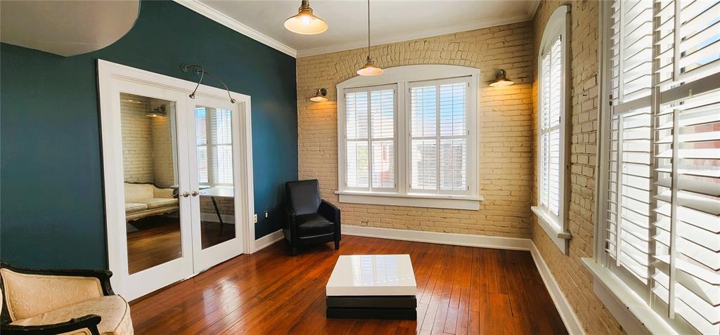 A room with hardwood floors, exposed brick walls, a dark accent wall, and white shutters — 241 E PARK AVENUE, LAKE WALES, FL