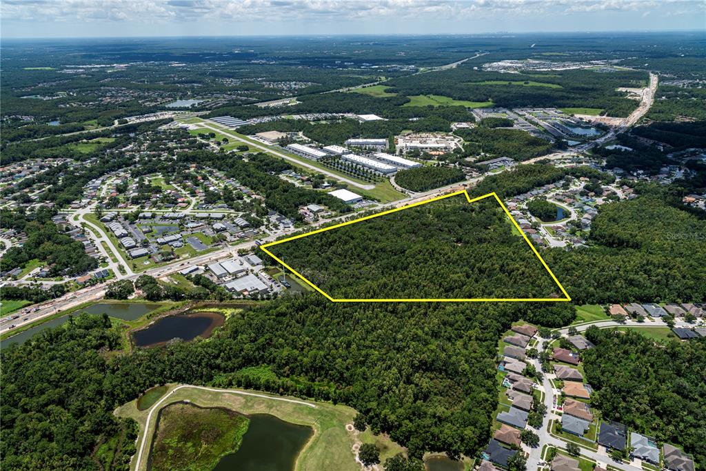 An aerial view shows a large, wooded plot of land outlined in yellow near residential areas — N/A N/A, LAND O LAKES, FL