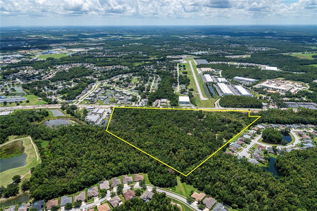 An aerial view shows a large, wooded plot of land outlined in yellow near residential neighborhoods — N/A N/A, LAND O LAKES, FL