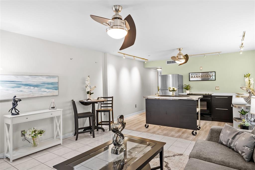 An open-concept living and kitchen area features tile flooring, a ceiling fan, and a kitchen island — 426 32ND AVENUE N UNIT 102E, ST PETERSBURG, FL