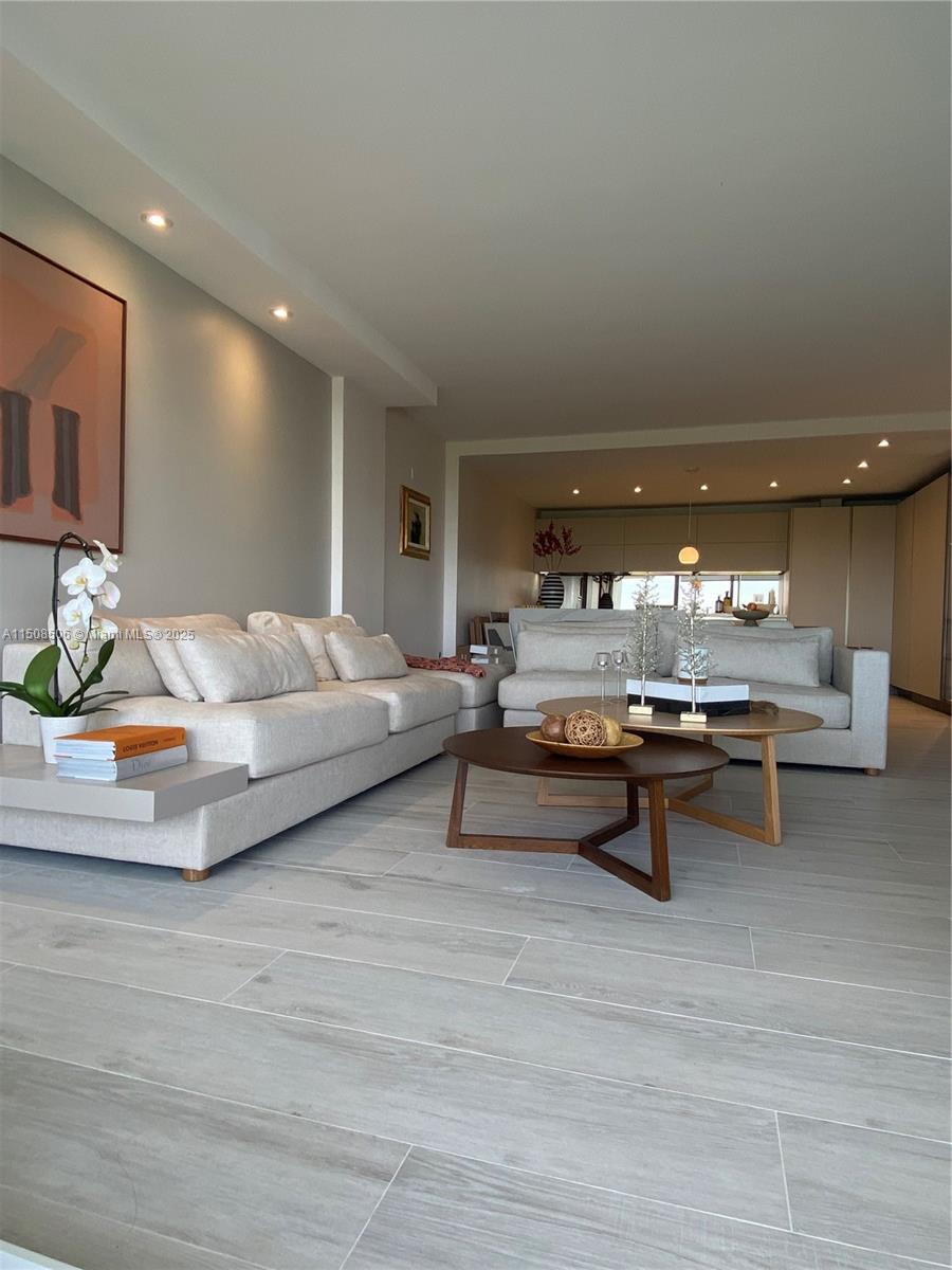A living room features light-colored sofas, two wooden coffee tables, and light wood-look flooring — 199 Ocean Lane Dr # 1112, Key Biscayne FL 33149, KEY BISCAYNE, FL