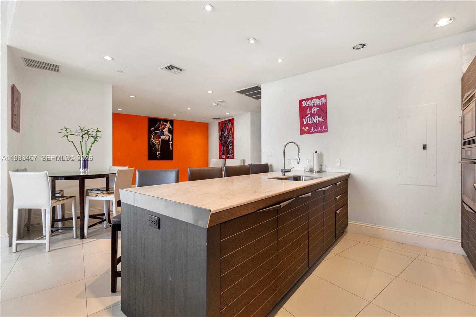 A modern kitchen features a dark wood island with a light countertop and bar seating — 200 Biscayne Boulevard Way # 4907, Miami FL 33131, MIAMI, FL