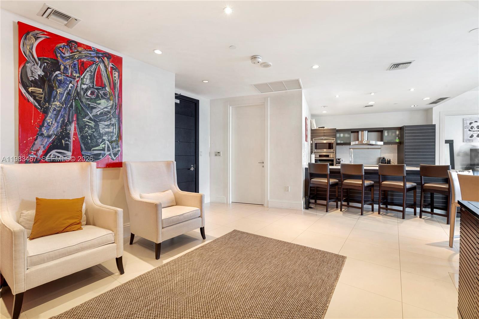 A living room with two armchairs, a rug, and an open kitchen with bar seating — 200 Biscayne Boulevard Way # 4907, Miami FL 33131, MIAMI, FL