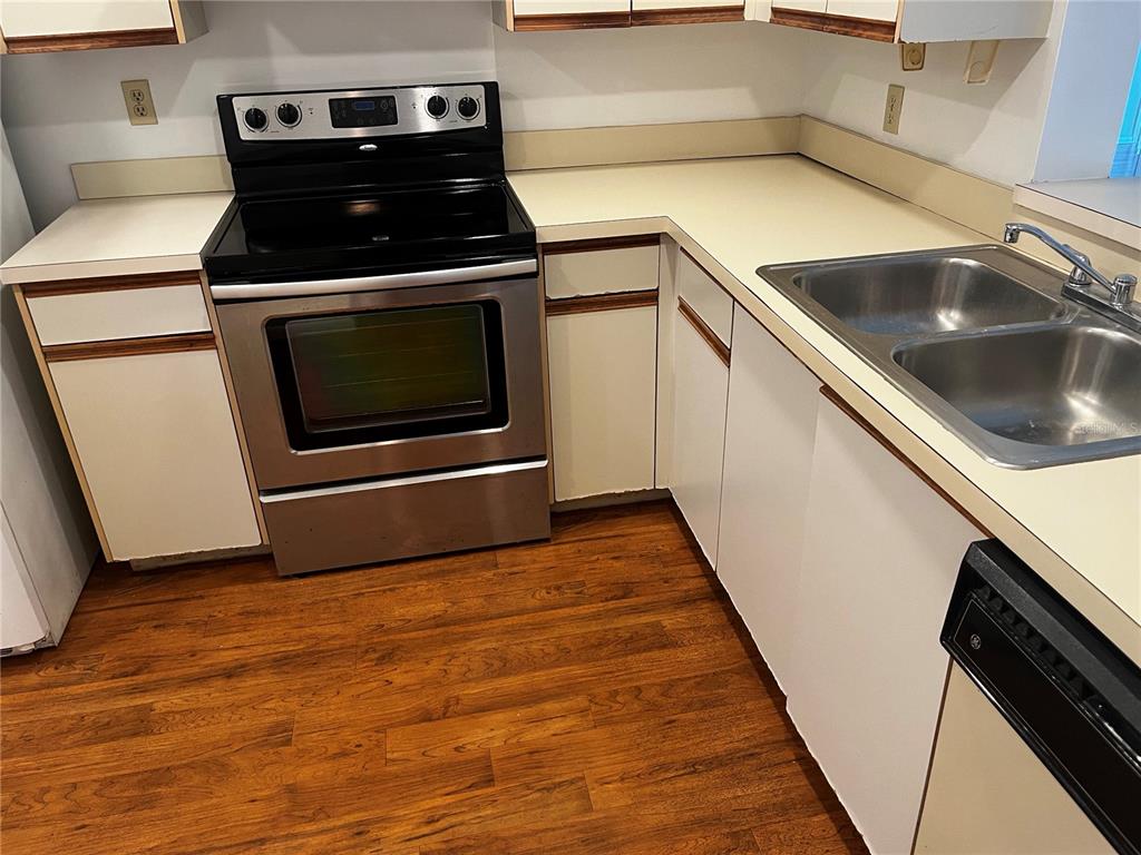 A kitchen features white cabinets, laminate countertops, stainless steel appliances, and wood-look flooring — 800 COVE CAY DRIVE UNIT 3F, CLEARWATER, FL