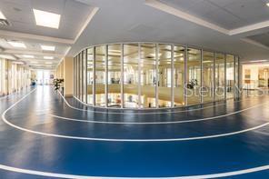 An indoor running track with blue flooring curves around a glass-enclosed atrium — 235 ANASTASIA DRIVE, POINCIANA, FL