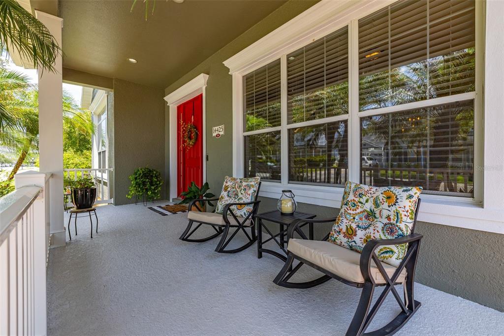 A living room with a blue sofa, white armchairs, a striped ottoman, and an open kitchen — 14425 MAILER BOULEVARD, ORLANDO, FL