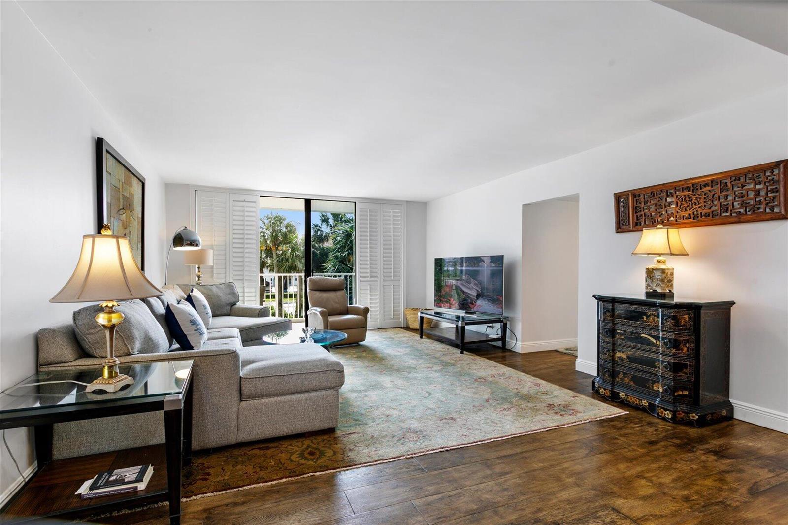 A living room features a grey sectional sofa, a patterned area rug, and hardwood floors — 2860 S Ocean Boulevard # 214, Palm Beach FL 33480, PALM BEACH, FL