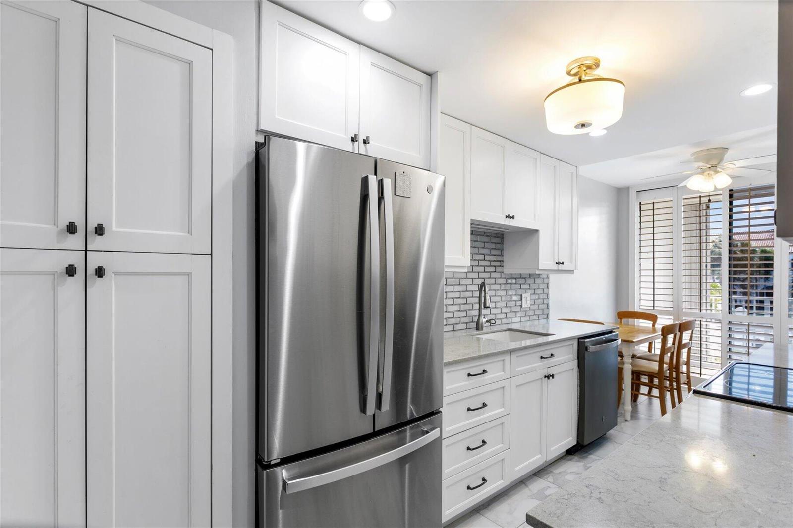 A modern kitchen features white cabinetry, stainless steel appliances, gray countertops, and a subway tile backsplash — 2860 S Ocean Boulevard # 214, Palm Beach FL 33480, PALM BEACH, FL