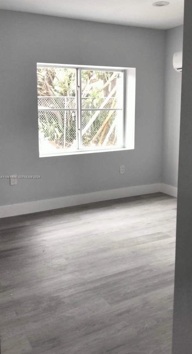 A bedroom with light gray walls, wood-look flooring, and a window overlooking a chain-link fence — 629 9th St, West Palm Beach FL 33401, WEST PALM BEACH, FL