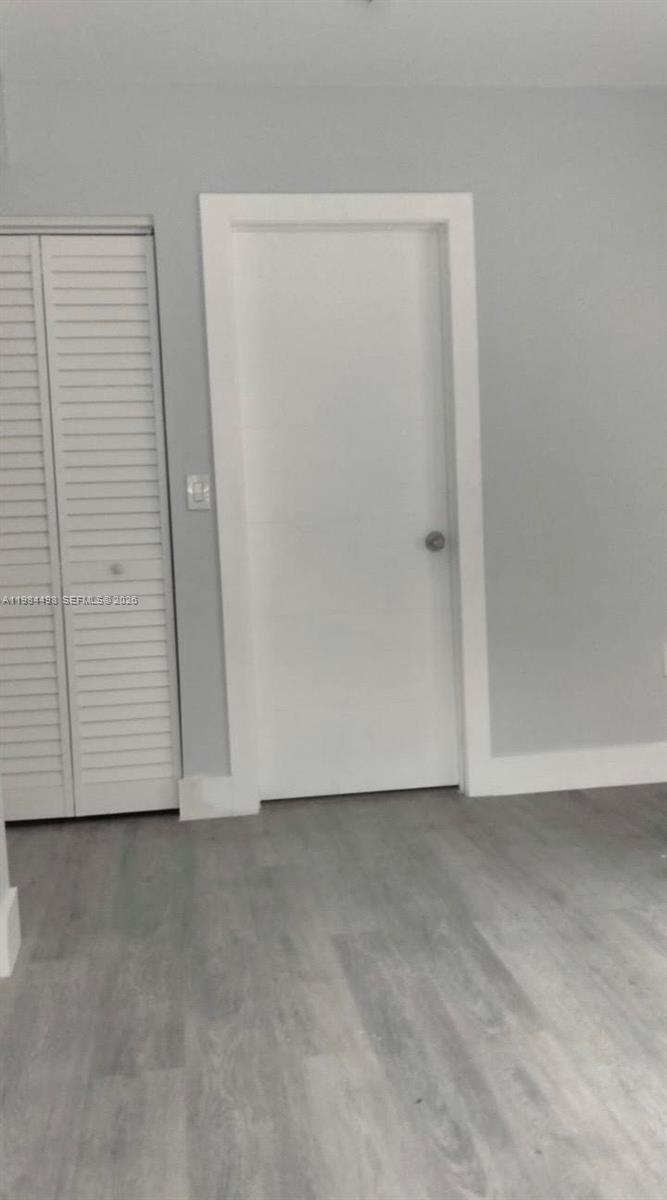 A room features gray walls, light wood-look flooring, a white door, and a louvered closet — 629 9th St, West Palm Beach FL 33401, WEST PALM BEACH, FL