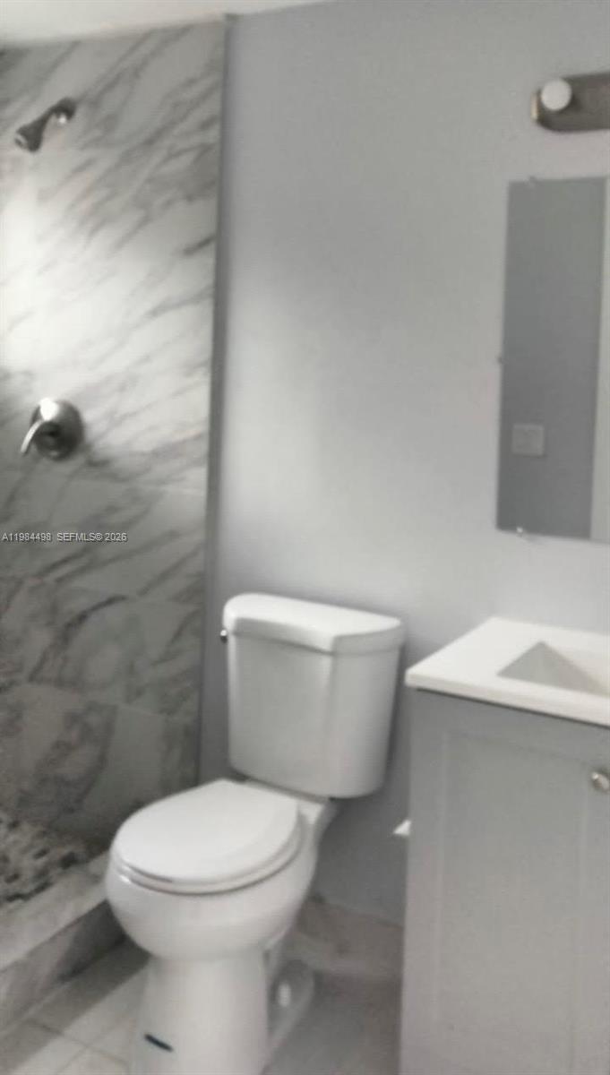 A bathroom features a marble-tiled shower, a white toilet, and a grey vanity — 629 9th St, West Palm Beach FL 33401, WEST PALM BEACH, FL