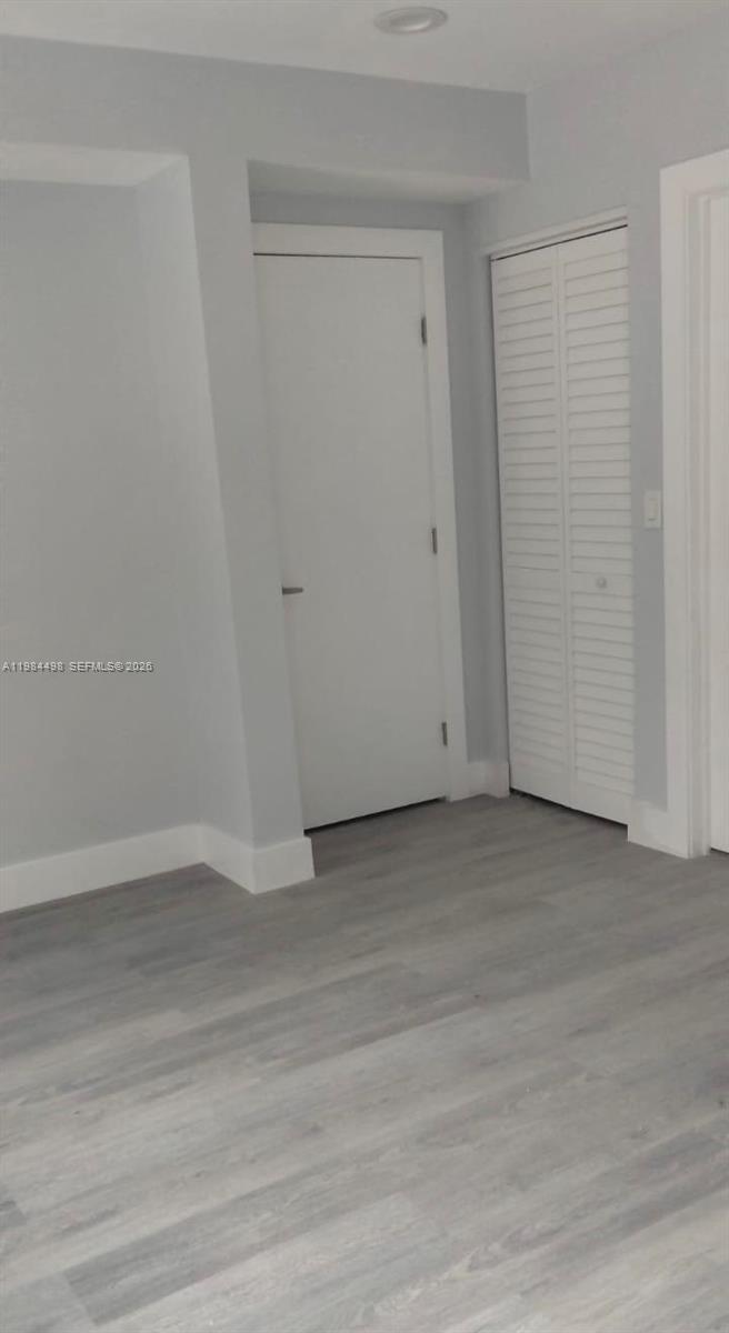 A room features light gray walls, wood-look flooring, a standard door, and a louvered closet door — 629 9th St, West Palm Beach FL 33401, WEST PALM BEACH, FL