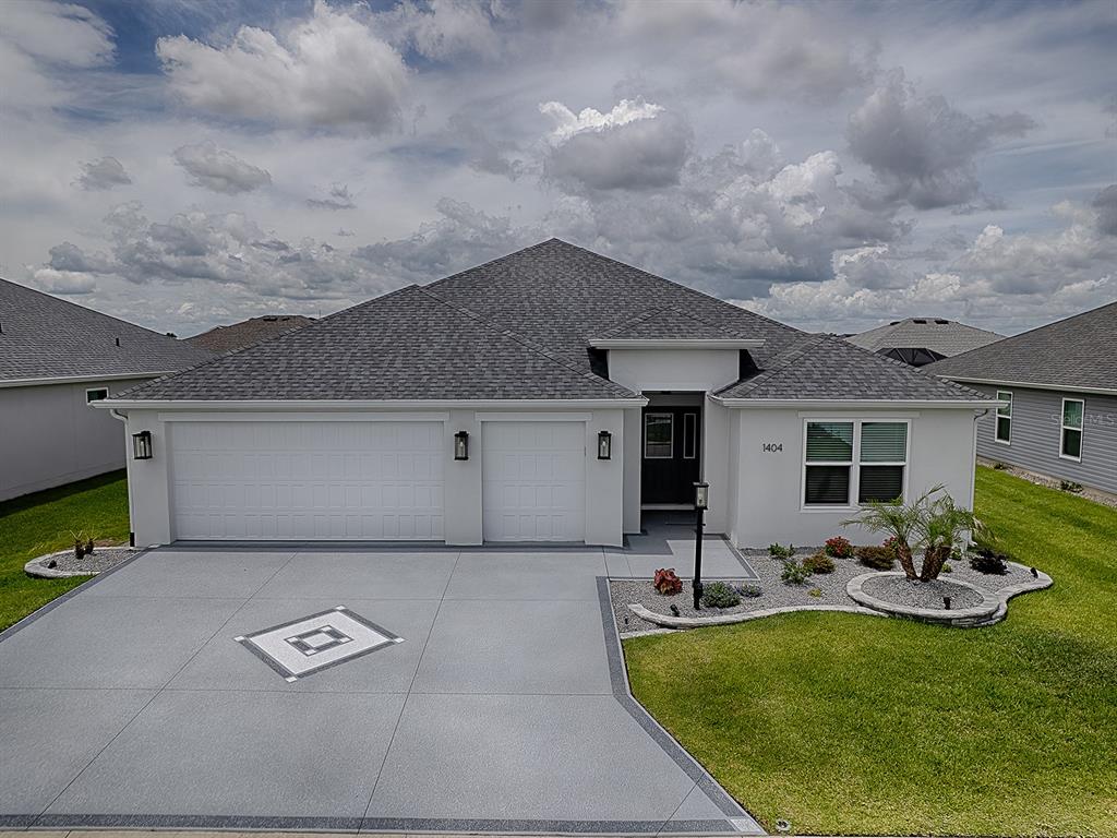 A single-story house with a gray roof, white stucco exterior, and a two-car garage — 1404 HEARNS LOOP, THE VILLAGES, FL