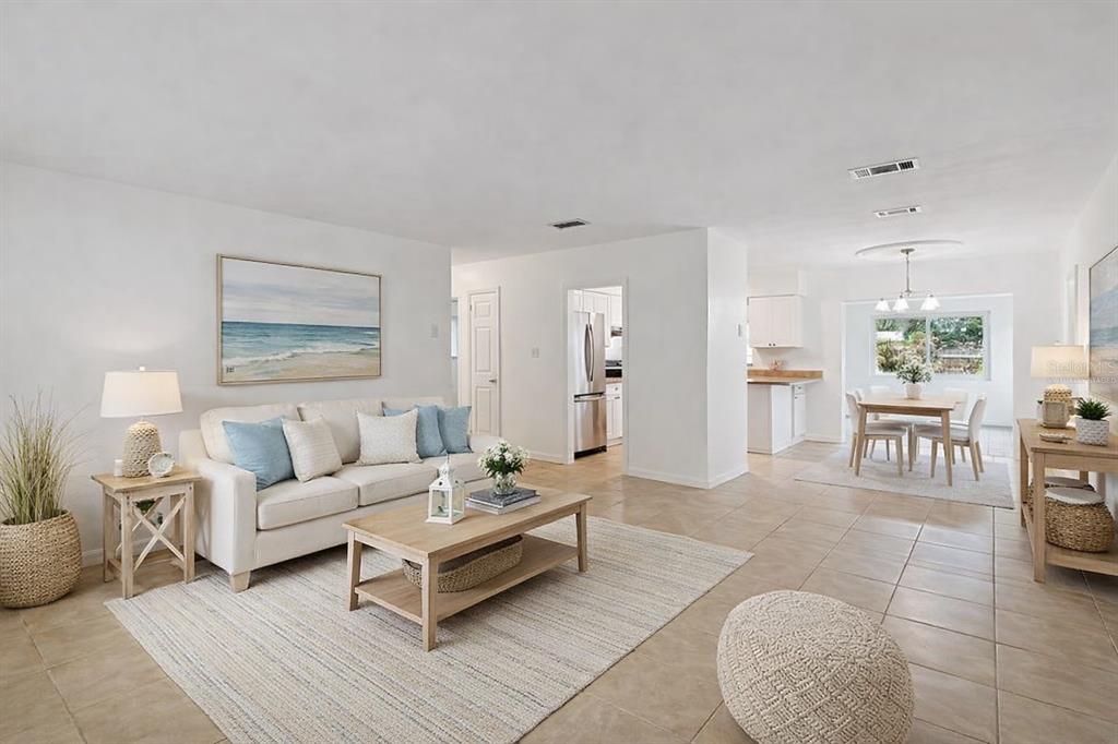An open-concept living and dining area features light tile floors, white walls, and coastal decor — 7232 DIANNE DRIVE, NEW PORT RICHEY, FL
