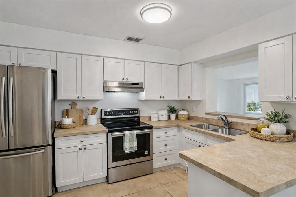 A kitchen features white cabinets, stainless steel appliances, and tan countertops — 7232 DIANNE DRIVE, NEW PORT RICHEY, FL