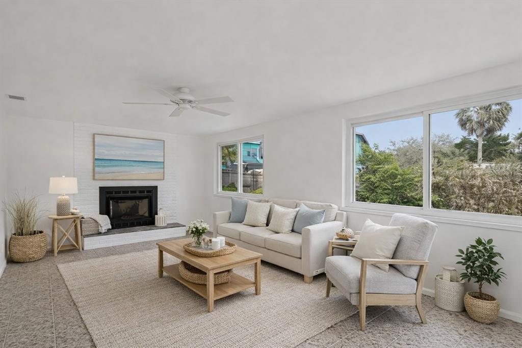 A bright living room features a white brick fireplace, a beige sofa, and large windows — 7232 DIANNE DRIVE, NEW PORT RICHEY, FL