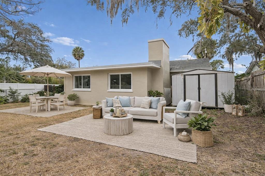 A backyard patio features a beige sofa, armchair, and dining set on a grassy lawn — 7232 DIANNE DRIVE, NEW PORT RICHEY, FL
