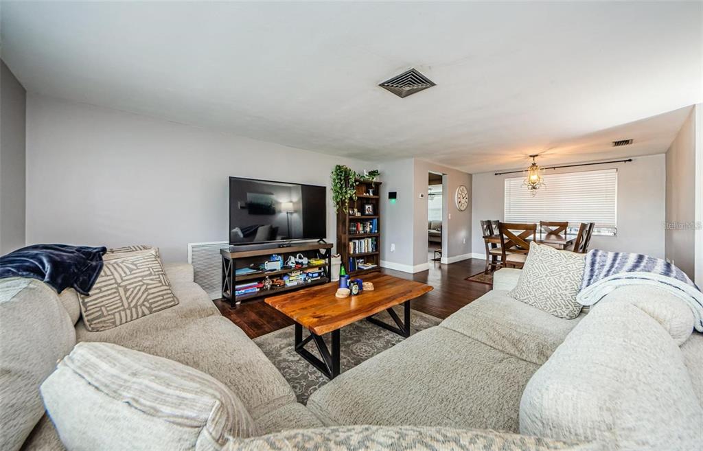 A living room features a sectional sofa, a wooden coffee table, and a television stand — 5915 OTIS DRIVE, NEW PORT RICHEY, FL