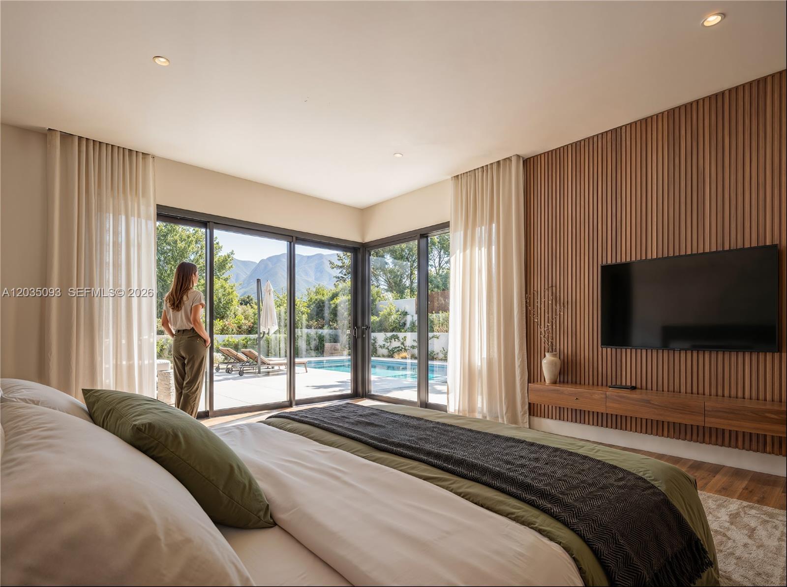 A bedroom features a wood-slatted accent wall, a television, and sliding glass doors overlooking a pool — 9445 SW 73rd Ave, Pinecrest FL 33156, PINECREST, FL
