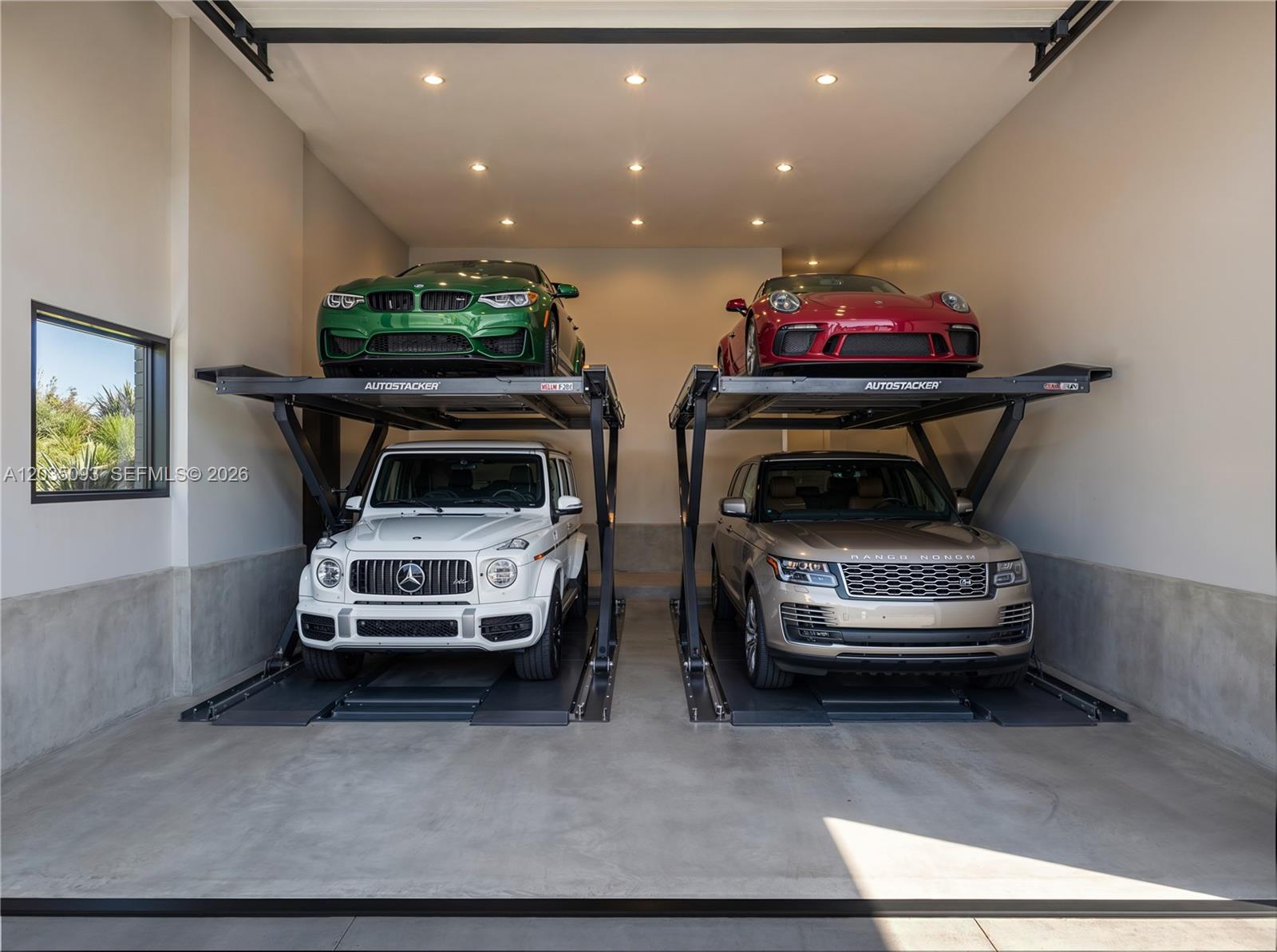 A garage features two car stacker lifts holding four luxury vehicles on concrete flooring — 9445 SW 73rd Ave, Pinecrest FL 33156, PINECREST, FL