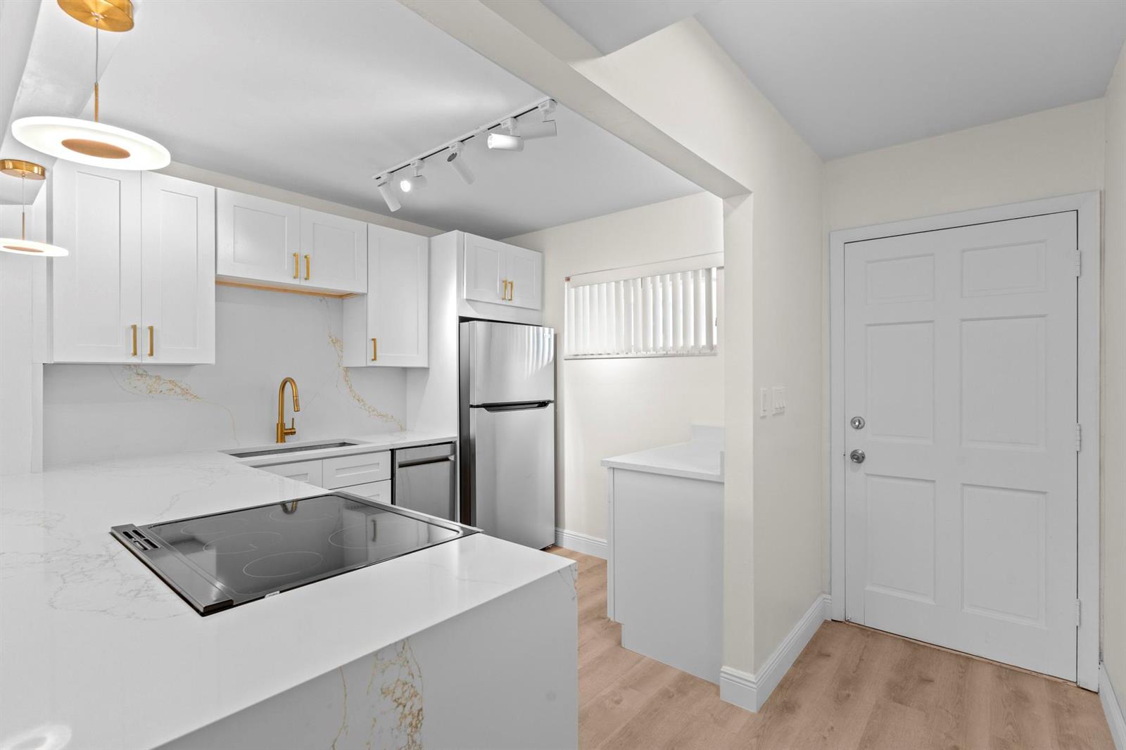 A modern kitchen features white cabinets, marble-patterned countertops, stainless steel appliances, and wood-look flooring — 2647 Garden Drive # 101, Lake Worth FL 33461, LAKE WORTH, FL