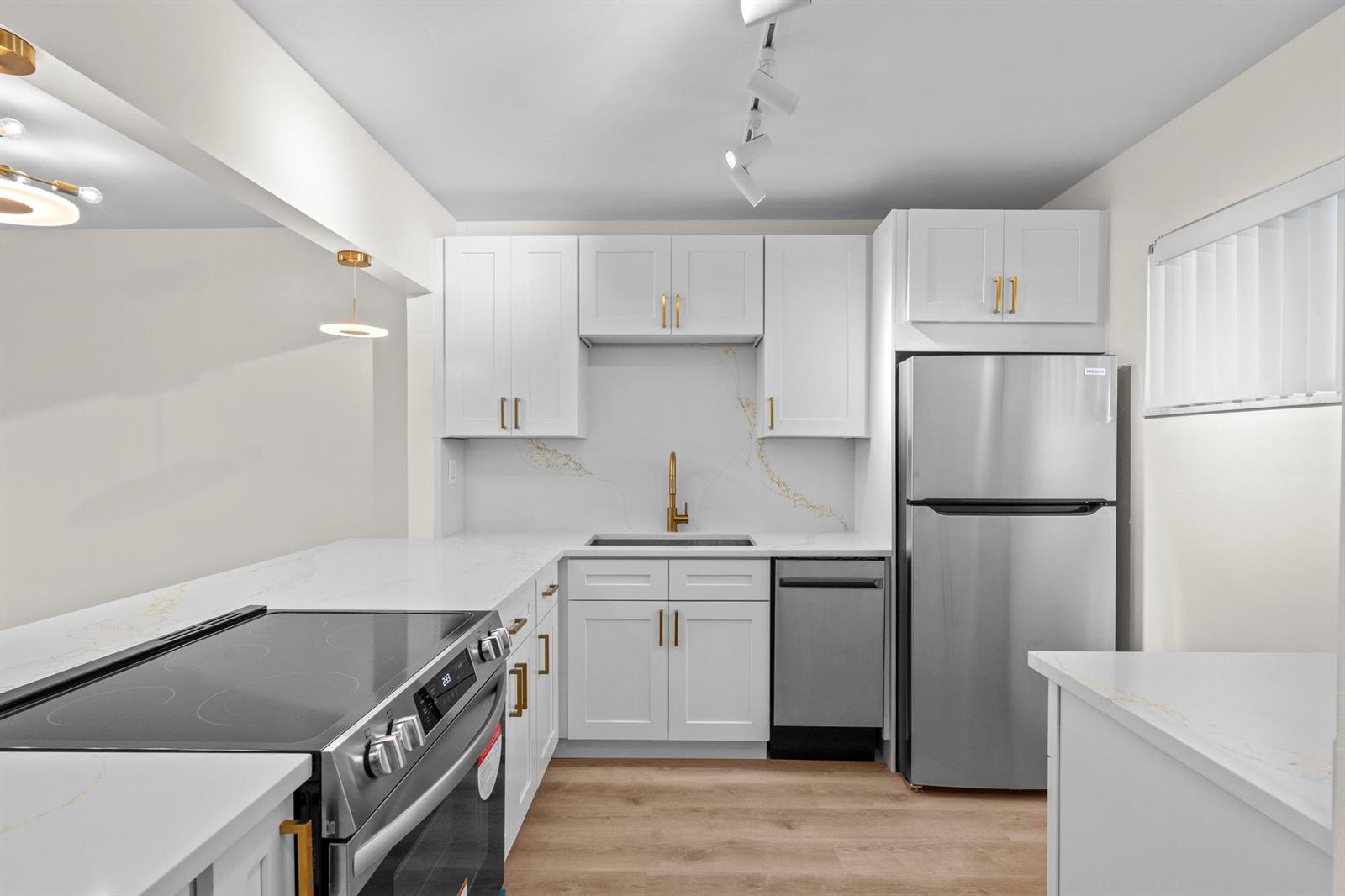 A modern kitchen features white cabinets, stainless steel appliances, and gold hardware — 2647 Garden Drive # 101, Lake Worth FL 33461, LAKE WORTH, FL