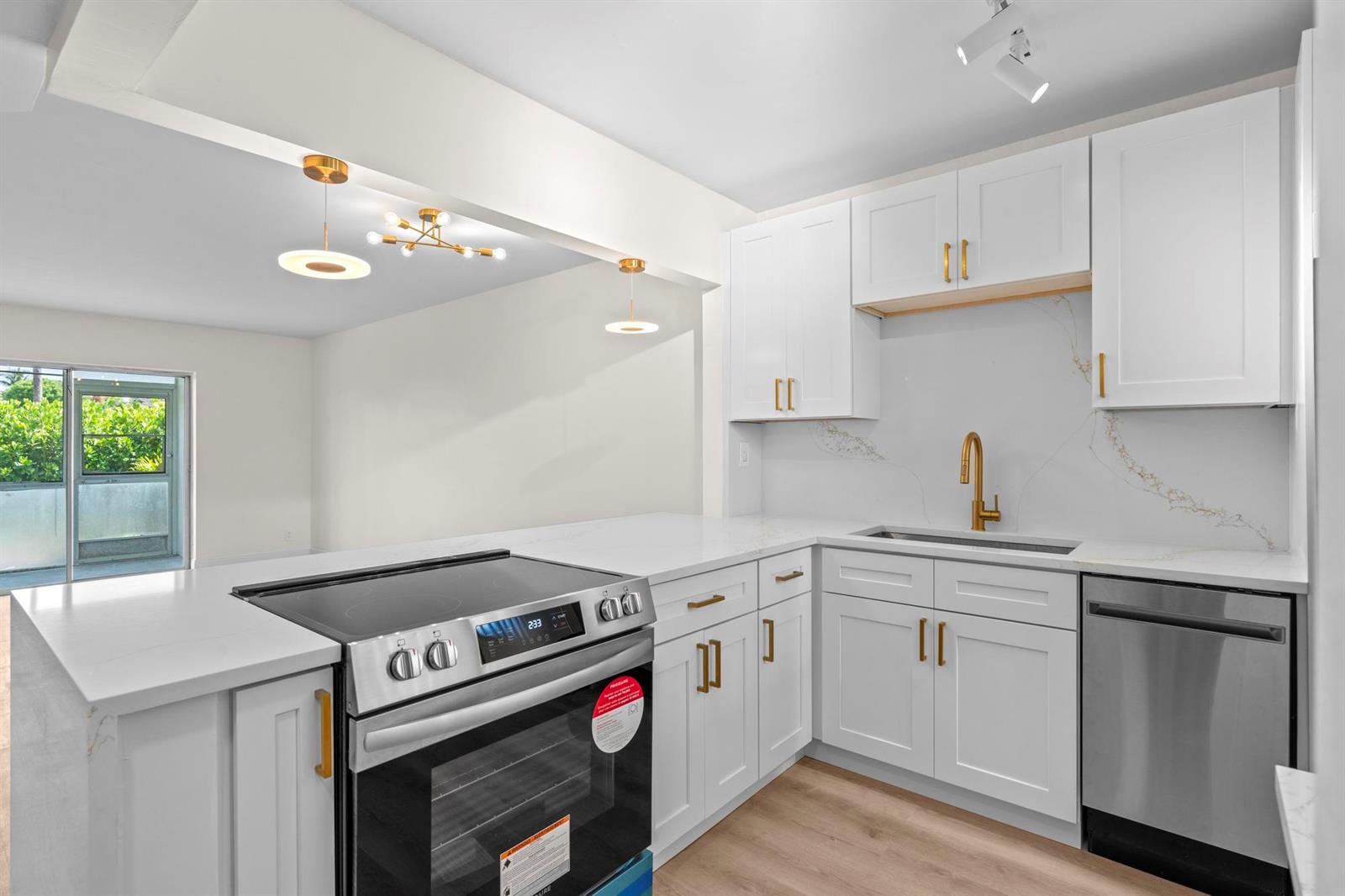 A modern kitchen features white cabinets, gold hardware, stainless steel appliances, and quartz countertops — 2647 Garden Drive # 101, Lake Worth FL 33461, LAKE WORTH, FL