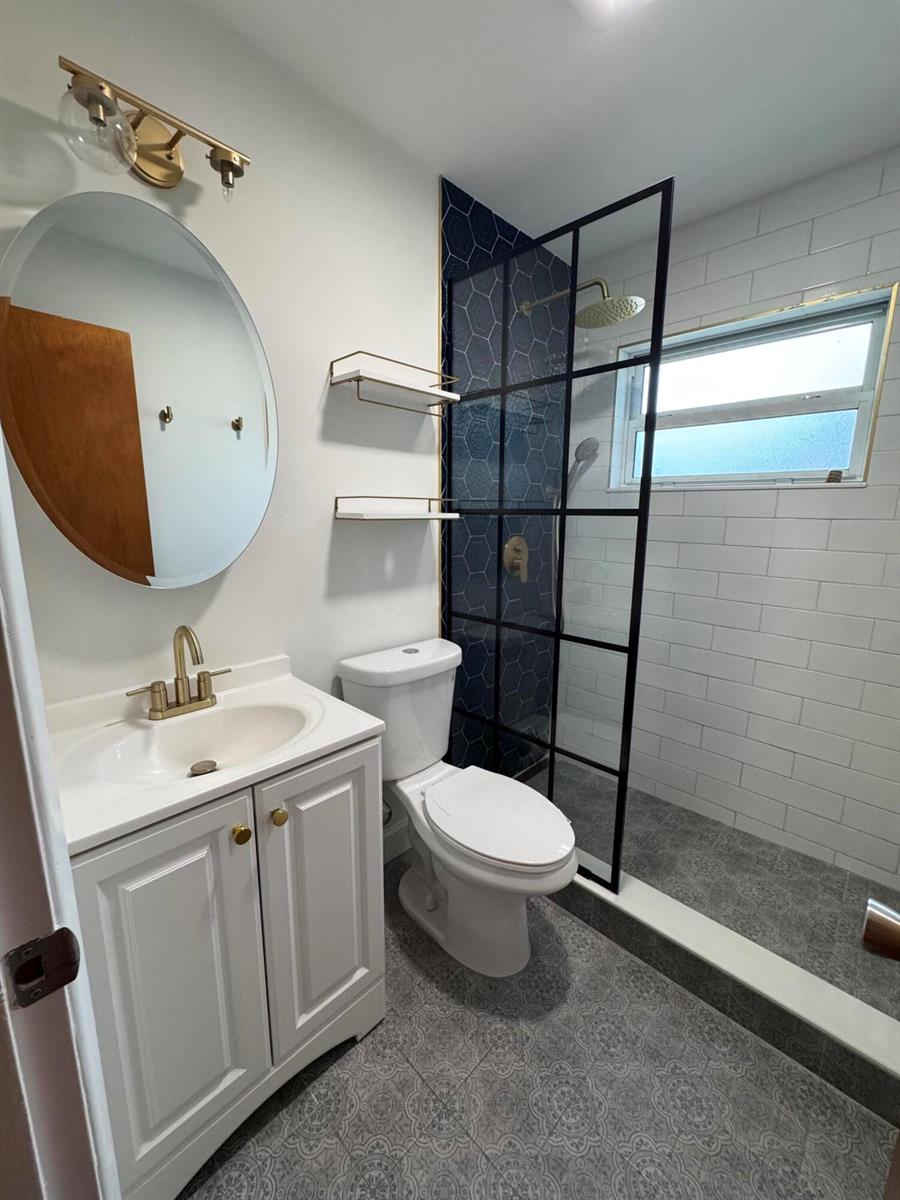 An empty living room features light wood-look flooring, white walls, and a front entry door — 4353 Broadway Street, Lake Worth FL 33461, LAKE WORTH, FL