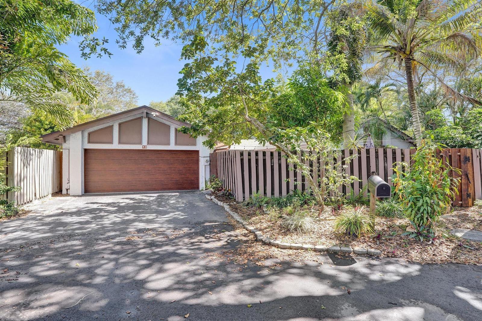 A paved driveway leads to a garage with a wood-paneled door and a wooden fence — 43 Birch Drive, Cooper City FL 33026, COOPER CITY, FL
