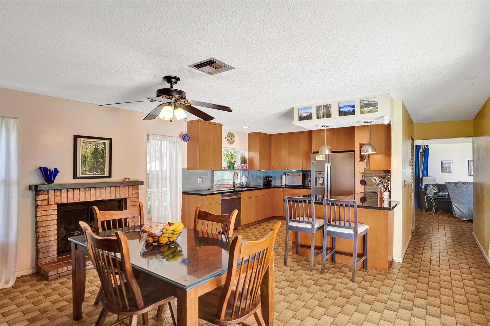 A kitchen and dining area features wood cabinets, a brick fireplace, and tile flooring — 43 Birch Drive, Cooper City FL 33026, COOPER CITY, FL