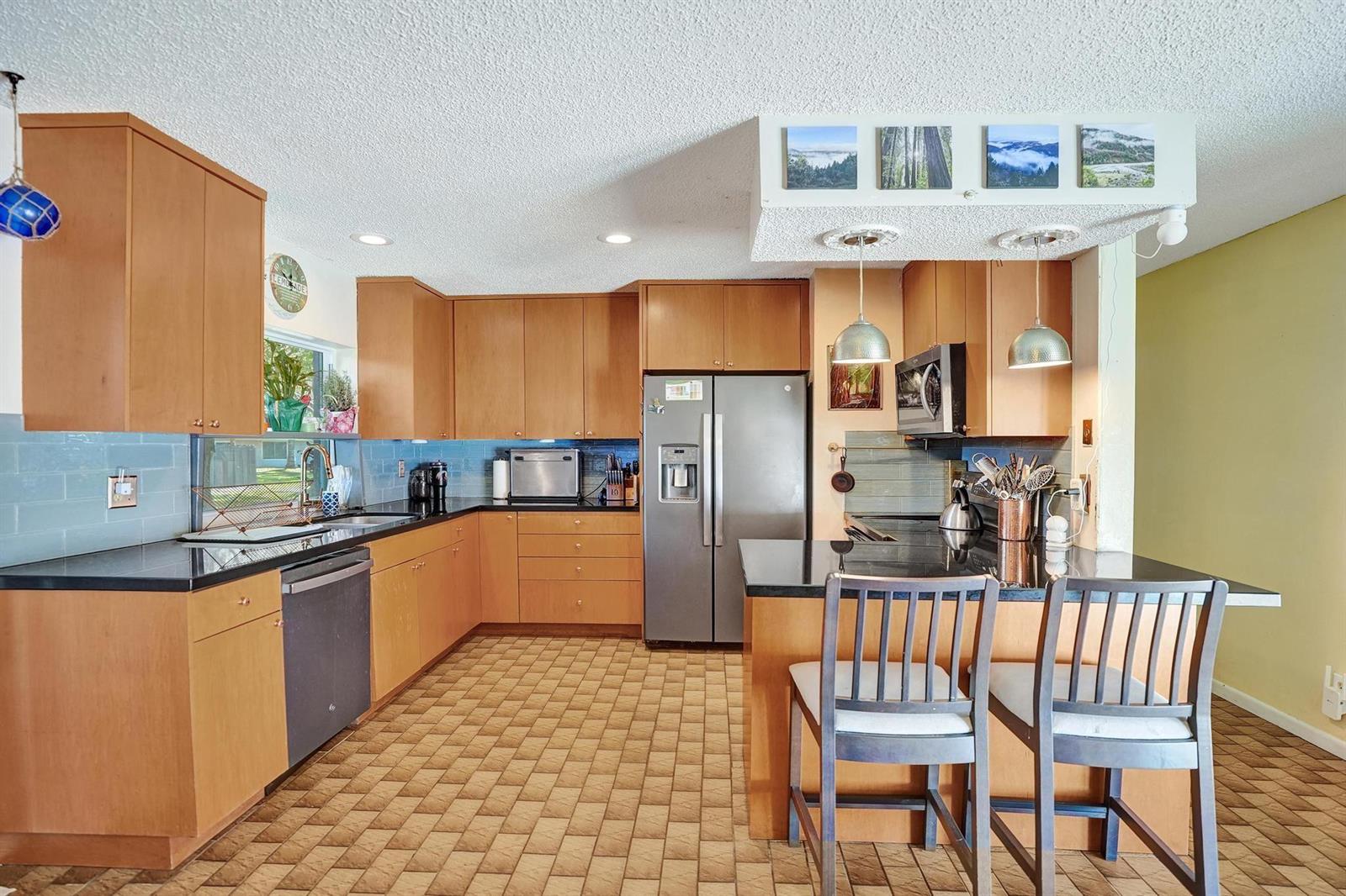 A kitchen features light wood cabinets, black countertops, a stainless steel refrigerator, and tiled flooring — 43 Birch Drive, Cooper City FL 33026, COOPER CITY, FL