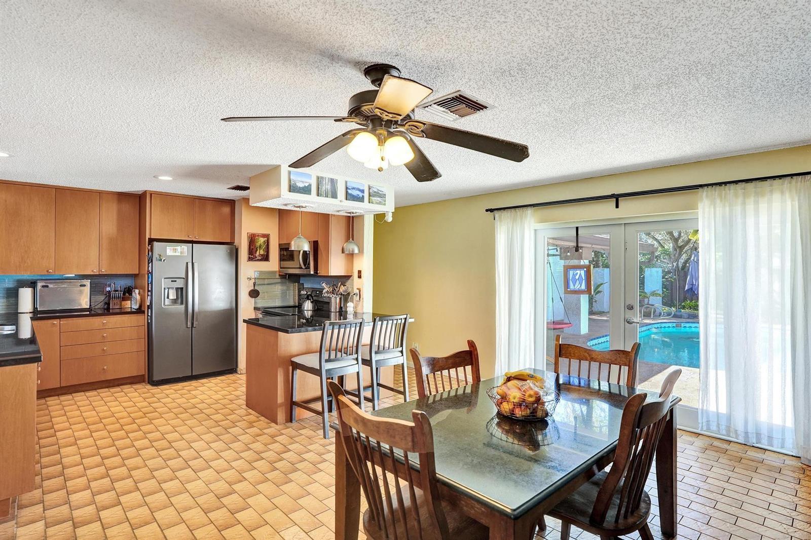 A kitchen and dining area with wood cabinets, tile floors, and a view of a pool — 43 Birch Drive, Cooper City FL 33026, COOPER CITY, FL