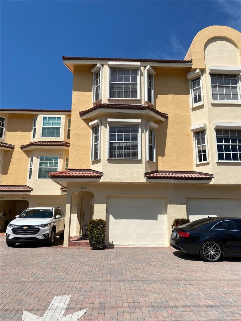 A three-story yellow townhouse with a garage and a brick-paved driveway — 4230 N Ocean Drive, Hollywood FL 33019, HOLLYWOOD, FL