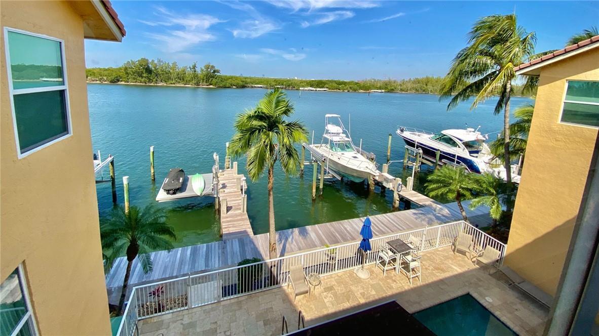 An elevated view of a waterfront patio with a pool, dock, and two boats — 4230 N Ocean Drive, Hollywood FL 33019, HOLLYWOOD, FL